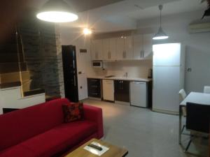 Atakum的住宿－Güzel Yalı Evleri Residence &Apart Hotel，一间带红色沙发的客厅和一间厨房