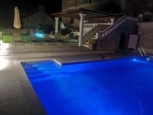 a blue swimming pool at night with a table and chairs at casa salvante in Moaña