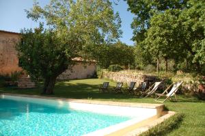 a swimming pool in a yard with chairs and a tree at Gli Archi in Monteriggioni