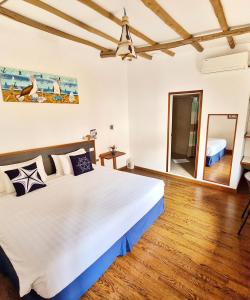 1 dormitorio con 1 cama blanca grande y suelo de madera en Capitan Max B&B, en Puerto Ayora