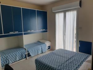 two beds in a room with blue cabinets and a window at Hotel Giannini in Rimini
