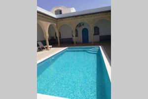 una piscina en un edificio con agua azul en Maison typiques (houche) avec piscine en Houmt El Souk