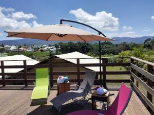 an umbrella and chairs on a deck with a view at EKOLODJ MANTEN in Lamentin