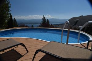 a swimming pool on a deck with two chairs at Les Chambres Roses in West Kelowna
