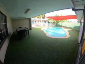 a swimming pool with a table and an umbrella at Coolabah Motel Townsville in Townsville