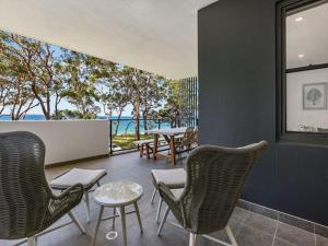 a room with chairs and tables and a view of the ocean at 204 on the Beach by Experience Jervis Bay in Huskisson