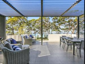 a patio with a table and chairs and a view of trees at Beachfront Luxury by Experience Jervis Bay in Huskisson