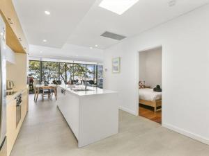 a kitchen and living room with white walls and a bedroom at Beachfront Luxury by Experience Jervis Bay in Huskisson