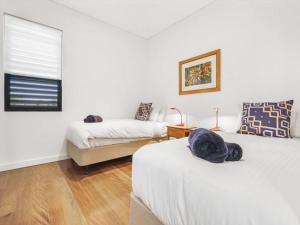 a bedroom with two beds and a window at Beachfront Luxury by Experience Jervis Bay in Huskisson