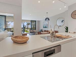 a kitchen with a counter with a sink and a living room at The Watermark by Experience Jervis Bay in Huskisson