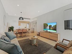 a living room with a couch and a flat screen tv at The Watermark by Experience Jervis Bay in Huskisson