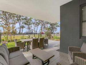 a patio with a couch and tables and chairs at The Watermark by Experience Jervis Bay in Huskisson
