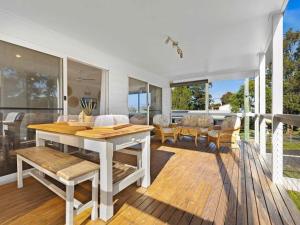 a dining room with a table and chairs on a deck at Centaur Sanctuary by Experience Jervis Bay in Sanctuary Point