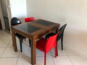 a wooden table with four red chairs around it at Apartamento Guarapari Frente para o Mar in Guarapari