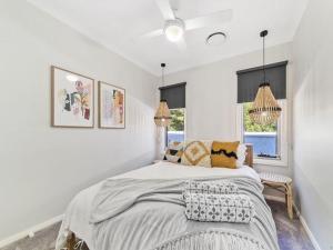 a white bedroom with a large bed and two windows at The Nest by Experience Jervis Bay in Erowal Bay