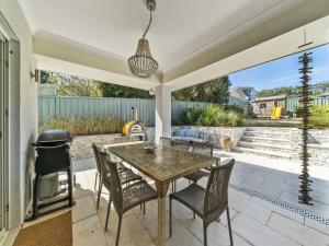 a patio with a table and chairs and a grill at The Nest by Experience Jervis Bay in Erowal Bay