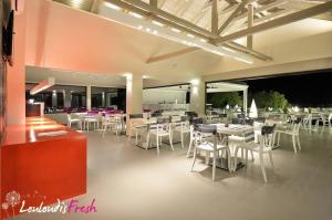a restaurant with white tables and white chairs at Louloudis Fresh-Adults Only in Skala Rachoniou