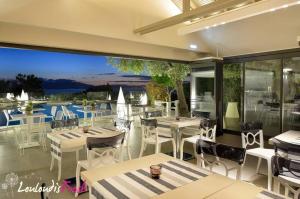 a restaurant with white tables and chairs and a large window at Louloudis Fresh-Adults Only in Skala Rachoniou