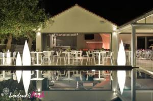 a group of tables and chairs in front of a house at Louloudis Fresh-Adults Only in Skala Rachoniou