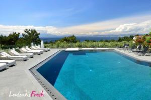a large swimming pool with lounge chairs and chairs at Louloudis Fresh-Adults Only in Skala Rachoniou