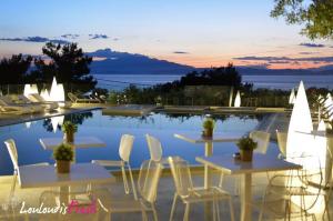 a group of tables and chairs next to a pool at Louloudis Fresh-Adults Only in Skala Rachoniou