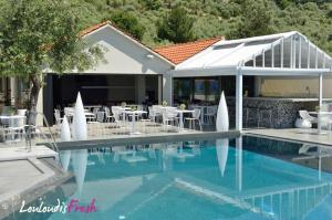 a swimming pool with tables and chairs next to a house at Louloudis Fresh-Adults Only in Skala Rachoniou