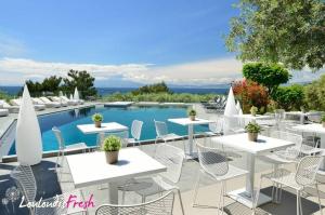 a group of tables and chairs next to a swimming pool at Louloudis Fresh-Adults Only in Skala Rachoniou
