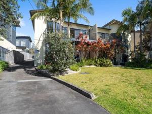 a house with palm trees and a grass yard at Portside at The Arc by Experience Jervis Bay in Vincentia