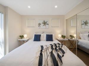 1 dormitorio con 1 cama blanca grande con almohadas azules en Portside at The Arc by Experience Jervis Bay, en Vincentia