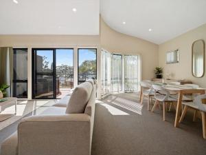 a living room with a table and a dining room at Portside at The Arc by Experience Jervis Bay in Vincentia