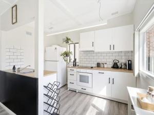 a kitchen with white cabinets and a black and white refrigerator at The Shack by Experience Jervis Bay in Vincentia