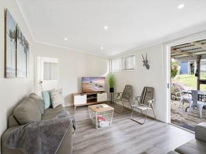 a living room with a couch and a tv at The Shack by Experience Jervis Bay in Vincentia