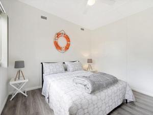 a white bedroom with a bed and a mirror on the wall at The Shack by Experience Jervis Bay in Vincentia