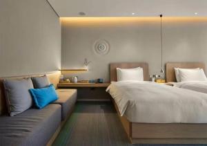 a hotel room with two beds and a couch at Ebo Hotel in Hangzhou