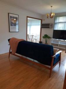 キャンベルタウンにあるCAMPBELLTOWN HOLIDAY HOME 3 BED + FREE PARKING NCA039のウッドフロアのリビングルーム(青いソファ付)