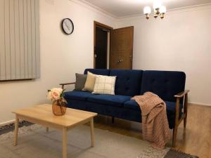 a blue couch in a living room with a table at CAMPBELLTOWN HOLIDAY HOME 3 BED + FREE PARKING NCA039 in Campbelltown