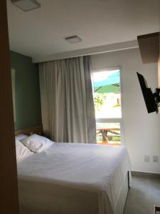 ein Schlafzimmer mit einem Bett und einem Fenster mit einem Regenschirm in der Unterkunft Muro Alto Condomínio Clube in Porto De Galinhas