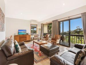 a living room with leather furniture and a balcony at Alva Lee by Experience Jervis Bay in Vincentia
