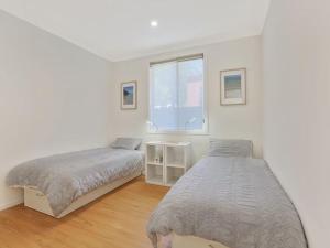 a white bedroom with two beds and a window at Banksia on Blenheim by Experience Jervis Bay in Vincentia