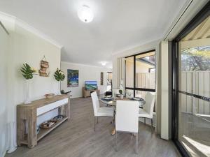 a dining room with a table and chairs and a window at Escape to Janeli by Experience Jervis Bay in Vincentia +6 photos
