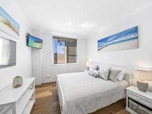 a white bedroom with a bed and two windows at Vincentia Retreat by Experience Jervis Bay in Vincentia