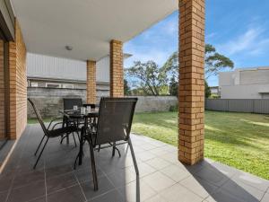 a patio with a table and chairs on it at Ammos by Experience Jervis Bay in Vincentia +7 photos