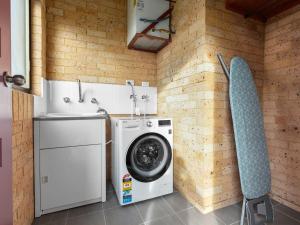 a laundry room with a washing machine and a chair at Ammos by Experience Jervis Bay in Vincentia
