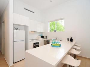 a white kitchen with a white counter and a white refrigerator at Bombara by Experience Jervis Bay in Huskisson