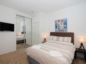 a white bedroom with a large bed and a mirror at Bombara by Experience Jervis Bay in Huskisson