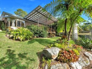 a house with atropical garden in front of it at The Sanctuary at Greenfield Beach by Experience Jervis Bay in Vincentia