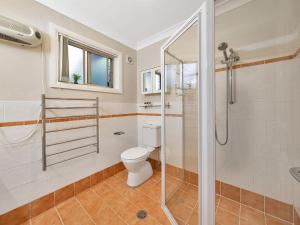 a bathroom with a toilet and a glass shower at The Sanctuary at Greenfield Beach by Experience Jervis Bay in Vincentia