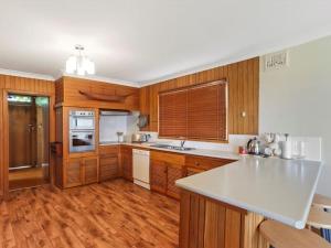 a kitchen with wooden cabinets and a white counter top at Summer Breeze by Experience Jervis Bay in Vincentia