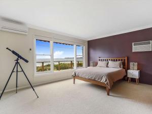 a bedroom with a large bed and a telescope at Summer Breeze by Experience Jervis Bay in Vincentia