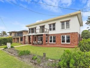 a large brick and white house with a yard at Summer Breeze by Experience Jervis Bay in Vincentia
